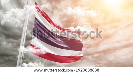 Thailand national flag cloth fabric waving on beautiful grey sky.