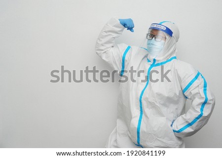 Frontliner in motivated mood in white blue stripe jumpsuit wearing transparent protective shield handling Covid-19 situation with clean white background and copyspace.
