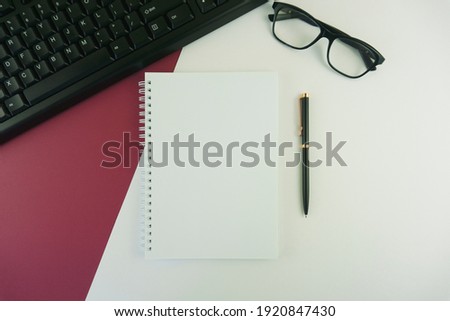 Computer Keyboard, Noted Pad, Pen on Multi Colored Background.