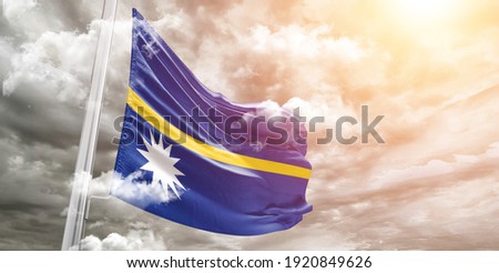 Nauru national flag cloth fabric waving on beautiful grey sky.