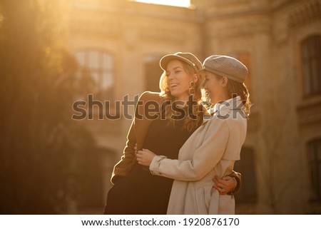 Two girls walking in city park and smiling. Autumn picture