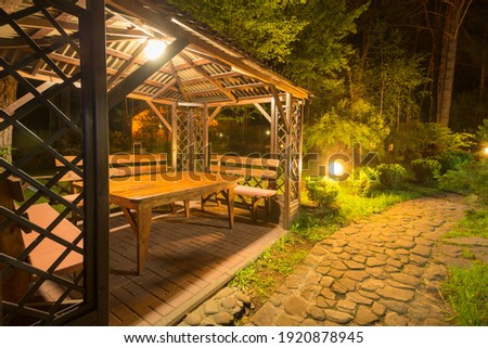 Stone path to the lighted cozy wooden patio gazebo in the backyard