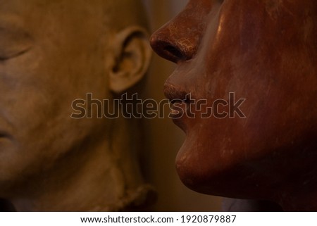 Female sculpture head detail with male silhouette on the background