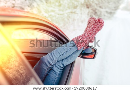 Young woman stuck her legs out of the car window in knitted woolen socks