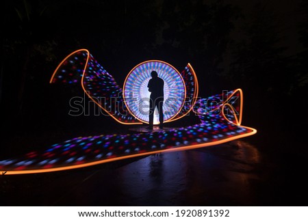 one person standing against beautiful orange and white circle light painting as the backdrop