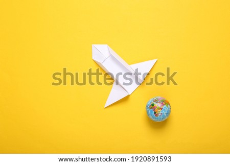 Origami space rocket shuttle and planet earth model on a yellow background. Space flight concept