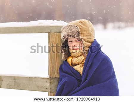 The boy froze in winter and wrapped in a blanket in the winter in the park Royalty-Free Stock Photo #1920904913