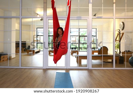 Woman instructor exercising poses for hammock yoga. Antigravity yoga for flexibility and healthy lifestyle. Aerial yoga to feel fit.