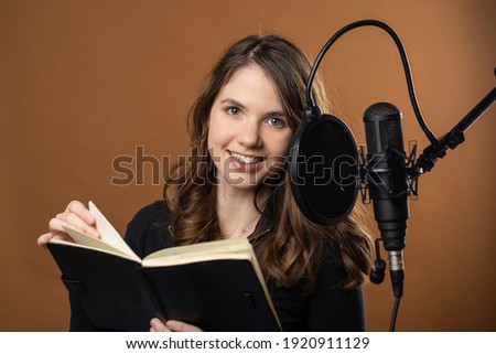 A young woman reads for a podcast as a voice actor  Royalty-Free Stock Photo #1920911129