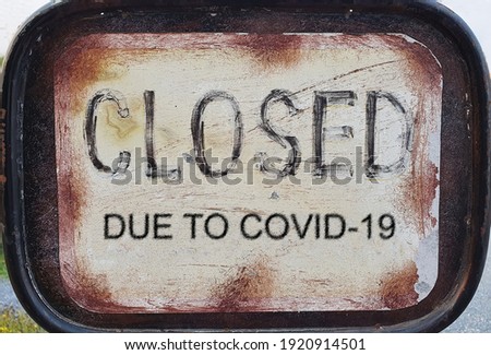 A rusted iron sign attached to the front of the shop. It is written in black, "Closed due to coVid-19" to inform consumers of the need for a store closure.