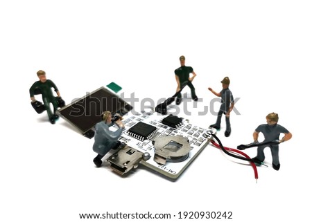 Miniature people working with electronic parts. Close up. Isolated white background.