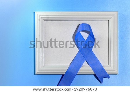 Blue ribbon with white frame on blue background with copy space. Colorectal Cancer Awareness. Colon cancer of older person. World diabetes day.