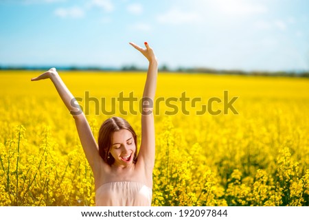 Beautiful happy girl having fun on the colza field. Healthy young woman outdoors. Countryside.