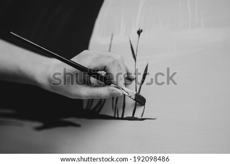 woman painter hand painting in her studio on canvas. black and white