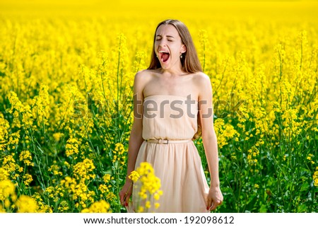 Beautiful happy girl having fun on the colza field. Healthy young woman outdoors. Countryside.