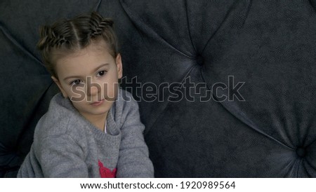 Little girl on the sofa, moody and sad.