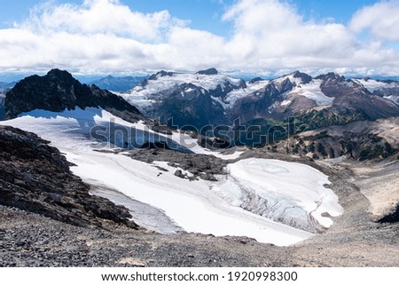 Clark Mountain and the Walrus Glacier can be seen behind an ice remnant on the summit of Buck Mountain. Glacier Peak Wilderness, Cascade Mountains, Washington