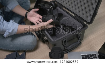 Cropped shot of man photographer hands putting camera accessories in the bag.