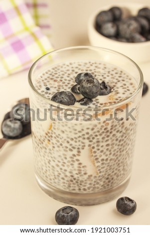 Healthy breakfast on a sunny morning. Chia seed pudding with blueberries and pieces of mango on white background. 