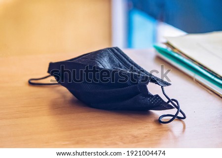 A black mask that has been worn on a wooden work table Royalty-Free Stock Photo #1921004474