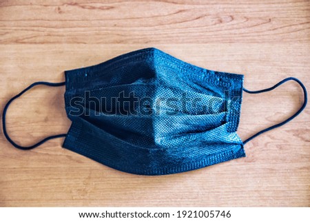 A black mask that has been worn on a wooden table Royalty-Free Stock Photo #1921005746