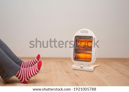 female feet standing on parquet floor, in front of halogen heater Royalty-Free Stock Photo #1921005788