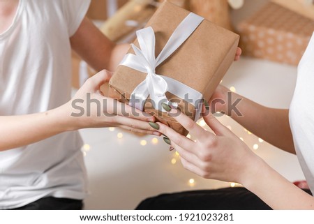 Cropped photo of Young man giving a gift box to his surprised happy woman. party moment. Hands of young boyfriend surprise in box with white ribbon to his girlfriend