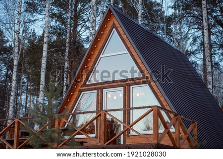 Contemporary new large country house standing in mixed forest in front of camera on background of pine trees and birches growing together Royalty-Free Stock Photo #1921028030