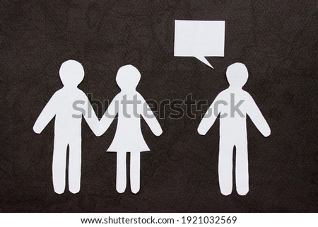Silhouettes of people cut from paper. Couple holding hands and next to a lonely man with speech-bubble over him. The concept of relationships, love, jealousy, loneliness, treason