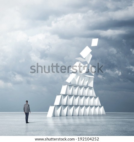 Businessman looks at house of cards
