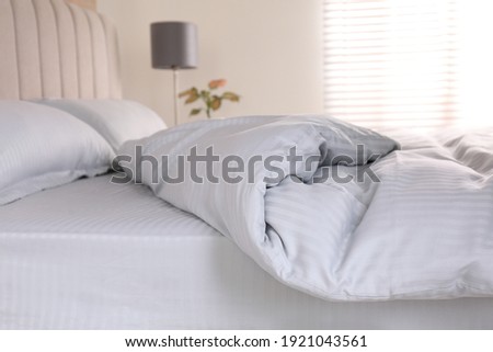 Comfortable bed with soft blanket indoors, closeup Royalty-Free Stock Photo #1921043561