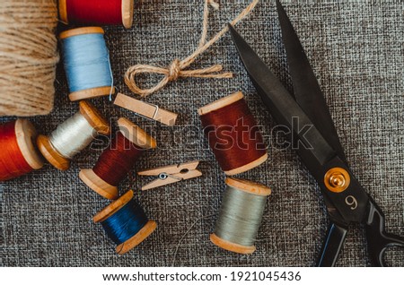 sewing tools. black scissors, spools of thread on baggy fabric. horizontal photo. Needlework tool. retro sewing tools: old scissors, bobbins of thread on gray fabric. Tailor. DIY.