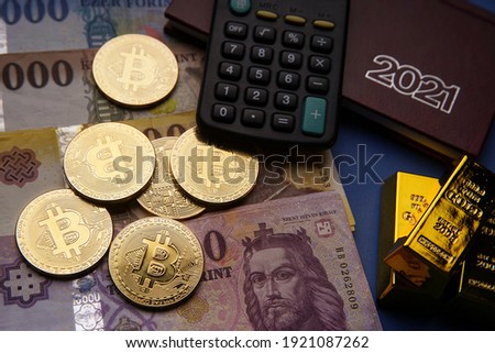 Hungarian forint paper money denomination, gold bars and bitcoin on a blue background. Bank image and photo.