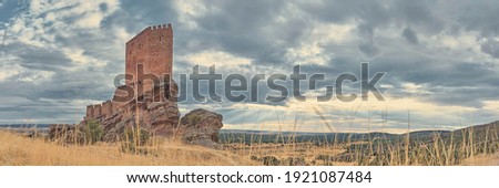 Panoramic view of a medieval castle on top of a hill and the sun's rays through the clouds. Zafra Castle