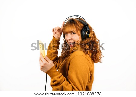 Medium shot of a redhead woman listening to music on her earphones on an isolated white background