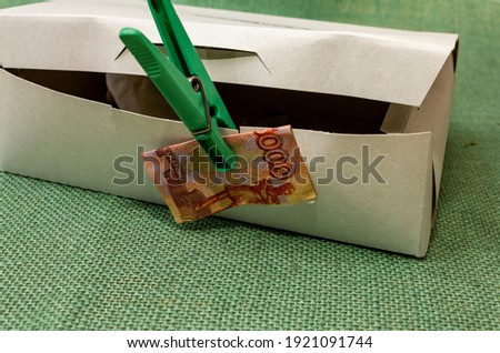 cardboard box with clothespin and banknote