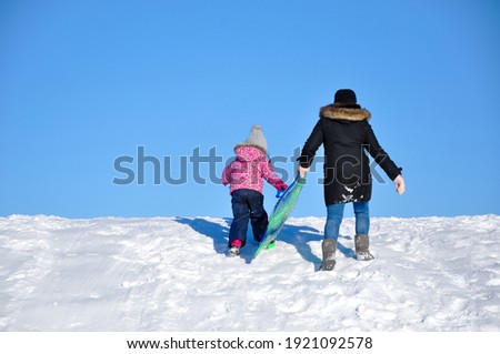 Mother and daughter going up in snowy hill