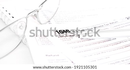 Tax form business financial concept with a pair of silver colored glasses and a pen aside.