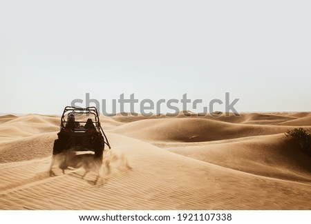 Silhouette of quad buggy bike at left side driving and drifting at safari sand dunes of Al Awir desert, Dubai, UAE, space for text
