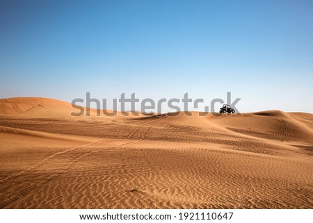 Desert sandy minimalistic landscape with one black buggy quad bike far and wheels traces, safari tour at wild nature Royalty-Free Stock Photo #1921110647