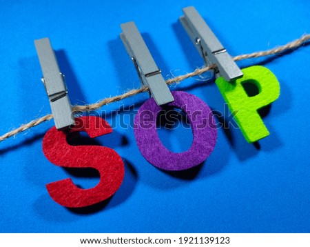 Selective focus.Word SOP (standard of procedure) with clothespins on blue background.Business concept.Shot were noise and film grain.