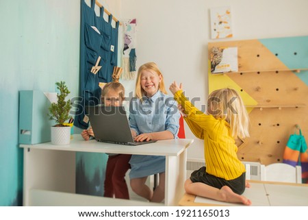 Kids receive education at home in a classroom with a laptop, online courses for children, child development, three Caucasian girls have fun and watch cartoons, homeshooling for children