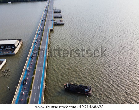 The view of the bridge with cars running and fishermen boats parked at sea, Transportation in Thailand.