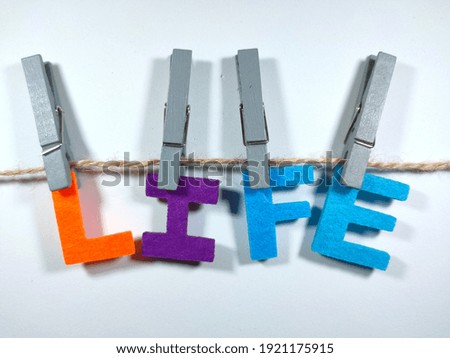 Selective focus.Word LIFE with clothespins on white background.Motivation concept.Shot were noise and film grain.