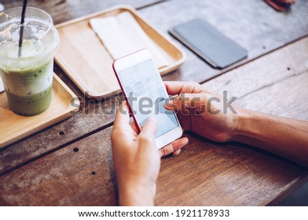 Business man hand use smartphone on wood table with ice green tea hand close up