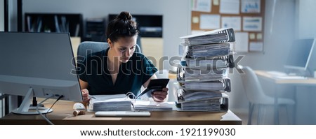 Young Businesswoman Working At Office With Stack Of Folders On Desk Royalty-Free Stock Photo #1921199030