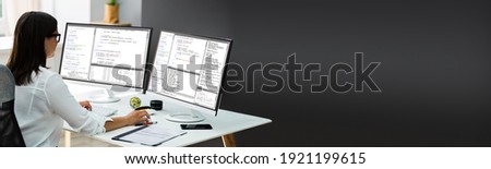 Computer Programmer In Office Using Multiple Monitor Screens