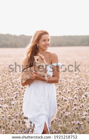 young beautiful woman with cute Chihuahua dog in nature in summer in a field of flowers