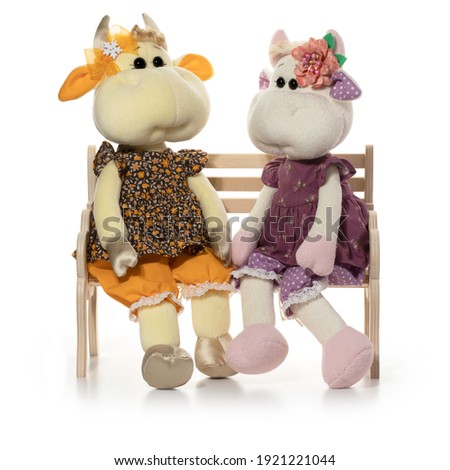Handmade toy cow sit on the bench. Full depth of field. With clipping path.