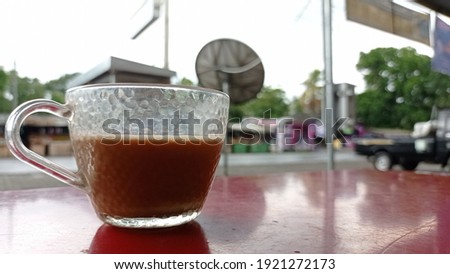a cup of milk coffee with cloudy weather and blurred background